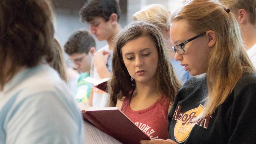 Students reading from booklet during church service